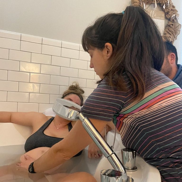 Waterbirth A woman in a bathtub receiving support during labor from a partner and a midwife.